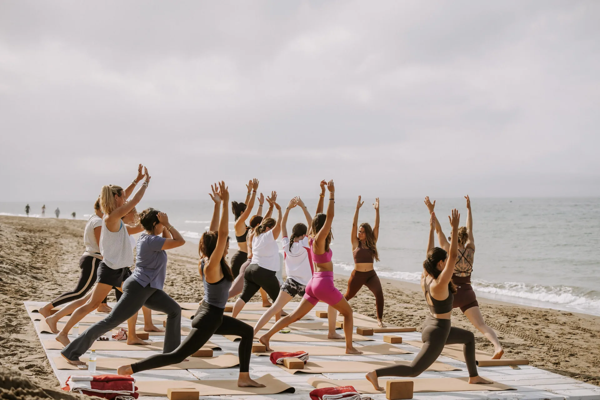 Alumnas de yoga de pie con los brazos alzados en la playa, durante una clase en Marbella