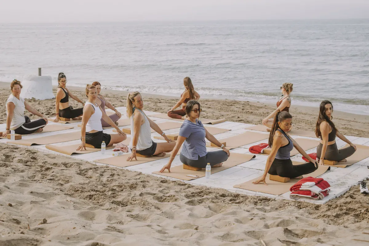 Grupo sentado durante una clase de yoga en la playa de Marbella